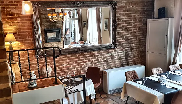 Dining room with brick wall, large mirror and laid tables
