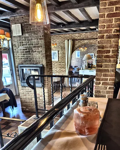 The open upper floor with wrought-iron railing, overlooking the room and the fireplace